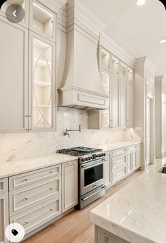 a large kitchen with white cabinets and marble counter tops, along with an island in the middle