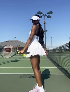 a woman standing on top of a tennis court holding a racquet and ball