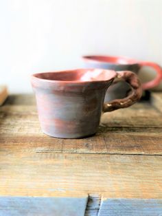 two brown and pink cups sitting on top of a wooden table next to each other