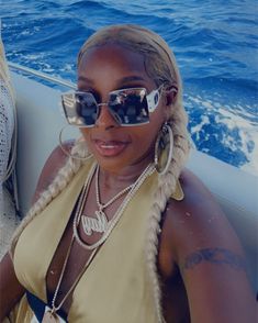 a woman wearing sunglasses sitting on a boat in the ocean next to another woman with long blonde hair