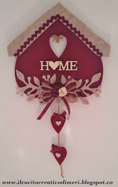 a red birdhouse shaped clock with the word home on it's face and heart decorations