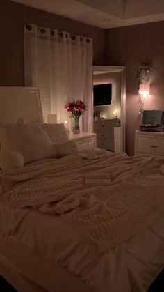 a bed with white sheets and pillows in a bedroom next to a window at night