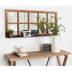 a wooden table topped with a mirror next to a vase filled with flowers and plants