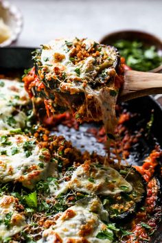 the skillet eggplant parmesan is being lifted with a wooden spoon