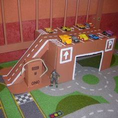 there is a cardboard race track with cars coming out of the tunnel and on top