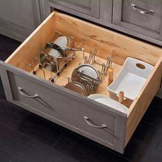 an open drawer in the middle of a kitchen with utensils and pans