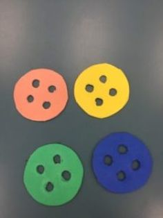 four different colored buttons sitting on top of a metal surface with holes in the middle