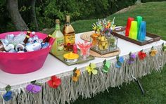 a table topped with lots of bottles and candy on top of a grass covered field