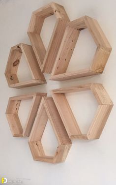 four wooden hexagons are arranged on the wall in order to be used as shelves