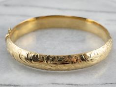 Stunning! The details on this vintage 18 karat gold bangle are simply gorgeous! Intricate botanical designs are engraved in warm yellow gold, covering the entire bracelet. Beautiful on its own or layered with other bracelets this piece is perfect for day or evening wear. Metal: 18K Yellow Gold Width: 11.1 mm Inside Circumference: 7 Inches Marks: "GERMANY 18KO " Stamped Luxury Engraved Yellow Gold Bracelets, Luxury Engraved Classic Braided Bracelets, Affordable Engraved Bangle Bracelets, Luxury Classic Gold Engraved Bracelet, Luxury Traditional Engraved Bangle, Cheap Handmade Antique Gold Jewelry, Cheap Antique Finish Gold Jewelry, Luxury Heirloom Gold Bracelet With Polished Finish, Luxury Gold Bracelets With Engraving Option