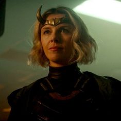 a woman in a black outfit with horns and horns on her head looking at the camera