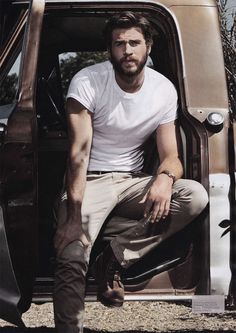 a man sitting in the back of a truck with his foot on the door handle