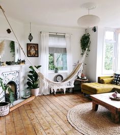 a living room filled with furniture and a hammock hanging from the ceiling over a fire place