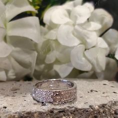 two wedding rings sitting on top of a stone slab next to white hydranges