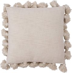 a white pillow with tassels on the front and back of it, against a white background