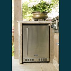 a stainless steel dishwasher sitting on top of a counter next to a potted plant