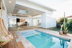 a backyard with a swimming pool, deck and wicker chair in the foreground