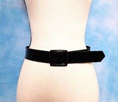 "A black, wide, faux patent leather cinch belt with a square slide buckle. Minimalist AF and an ABSOLUTE wardrobe essential. Good vintage condition. Decade: 1980s or 1990s Label: The Belt Factory Material: man made Closure: slide buckle Vintage Condition: very good (From a pet and smoke free home) Measurements are taken flat and doubled where necessary.  Waist range: 33\" maximum Width: 1.5\" Full length: 37\" Buckle dimensions: 2\" x 2\" NO RETURNS - ALL SALES ARE FINAL. Please check the measurements I've given, and measure yourself or a garment that fits you well to compare, before committing to buy. I do my best to clean garments and fix flaws as I am able. When I can't, I take care to note and photograph flaws, and price things accordingly. Please read descriptions carefully and look t 90s Belt, Strawberry Switchblade, Cinch Belt, 80s Dress, Suspender Belt, Belted Dress, Black Belt, Suspenders, Waist Size