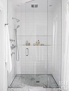 a white tiled bathroom with glass shower doors