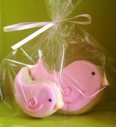 two decorated cookies with pink icing in a plastic bag