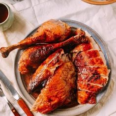 a plate that has some kind of chicken on it with sauce and utensils