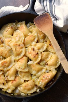 a skillet filled with tortellini shells on top of a wooden table