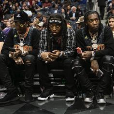 three men sitting next to each other at a basketball game