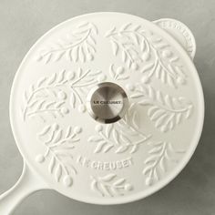 a white cast iron skillet with leaves on the bottom and words cruett