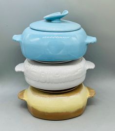 three ceramic dishes stacked on top of each other, one with a blue lid and the other white