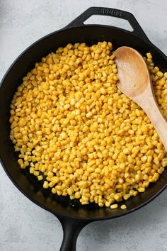 corn in a skillet with a wooden spoon