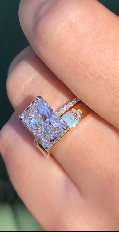 a woman's hand with a diamond ring on top of her finger and an engagement band