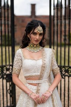 a woman in a white lehenga with gold jewelry on her neck and shoulders