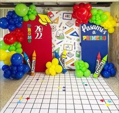 some balloons and other items are on the floor in front of a bulletin board with writing