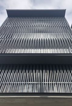 the side of a tall building with metal bars on it's sides and sky in the background