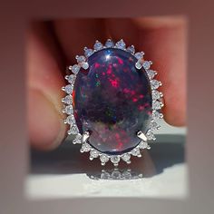 "★★Opal is one of the most favored gemstones among women. It is about the play of color in that natural Opal gemstone, that attracts the eyes,  you simply cannot take your eye off it. My love for unique gemstones brings me to look for unusual, one-of-a-kind gemstones, like the one set in this ring. ★★This 14k solid gold ring is set with a -  genuine - natural - huge - Ravishing - Ethiopian- One of kind-flashy black fire Opal. The kind of Opal that your eyes just can't get enough of. ★★This fire Opal weighs 10.3 carats in size 20x15 mm (0.75 inches). It is a large Ethiopian Opal ring, the Opal looks stunning in the sunlight. The colors it reveals in the sunlight are amazing blue, green, red, and gold. ★★The Opal is surrounded by 1.8 carats of natural high-grade nature 2 mm brilliant white d Formal Opal Ring With Gemstone Accents, Dazzling Opal Gemstone Ring Gift, Formal Opal Rings With Gemstone Accents, Formal Opal Ring With Diamond Accents, Dazzling Oval Opal Ring, Fusion Style Round Opal Ring, Black Fire Opal, Gold Opal Ring, Opal Diamond Ring