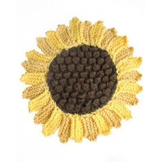 a crocheted sunflower with brown and yellow petals on the center, sitting in front of a white background