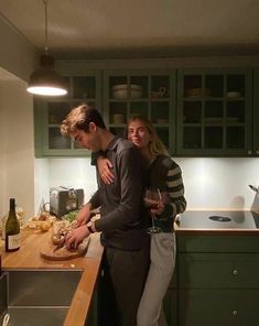 a man and woman standing in a kitchen next to a counter with food on it