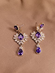 The earrings are three tiered with tear drop one and two carat amethyst stones and a zircon accented deco design.  Total 4 carats amethyst.  .88 carats zircon.  14K gold plated. Elegant Purple Jewelry For Formal Occasions, Elegant Purple Jewelry For Evening, Elegant Purple Evening Jewelry, Luxury Amethyst Teardrop Earrings, Elegant Amethyst Earrings For Formal Occasions, Purple Fine Jewelry Earrings For Formal Occasions, Elegant Purple Earrings For Pierced Ears, Elegant Purple Jewelry With Diamond Accents, Purple Drop Chandelier Earrings For Formal Occasions