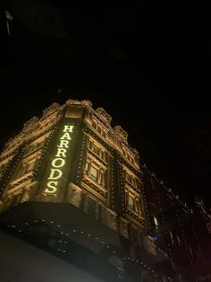 a tall building lit up at night with lights on it's sides and the words karrafood written in gold