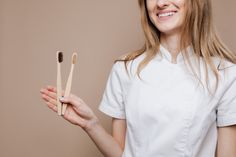 female dentist doctor holding a bamboo toothbrushes Download for free by clicking on the picture Free Design Resources #toothbrushe, #dentist, #eco More Photos on Kaboompics.com