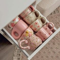 a box filled with lots of different kinds of coffee mugs on top of a carpeted floor