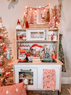 a christmas tree is next to a white toy kitchen