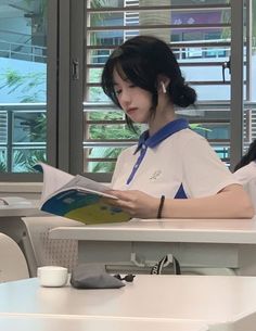 a woman sitting at a table reading a book