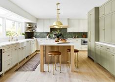 a large kitchen with white cabinets and wooden flooring is pictured in this image, there are two stools at the center of the island