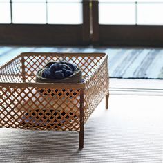 a basket that is sitting on the floor next to a window with some clothes in it