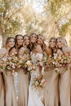 a group of women standing next to each other with bouquets in their hands and holding flowers