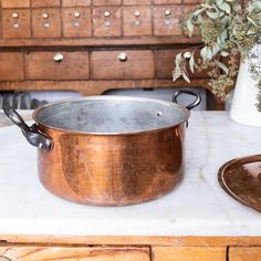 a large metal pot sitting on top of a counter next to a wooden drawer with drawers