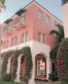 a pink building with lots of windows and plants