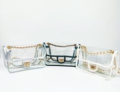 three clear purses with gold chains on the handles and sides, all lined up against a white background