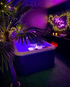 a hot tub in the middle of a room with purple lights on it and a palm tree next to it